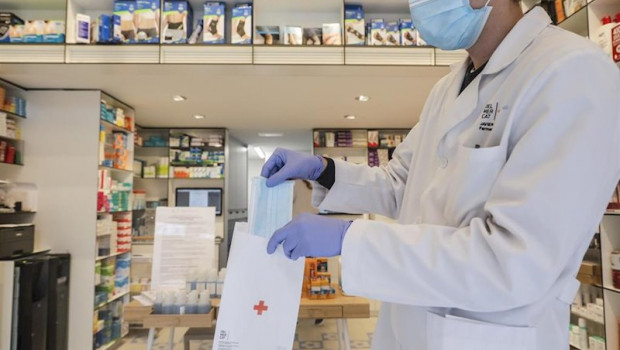 ep un farmaceutico da una mascarilla durante el reparto de mascarillas gratuitas contra el covid-19