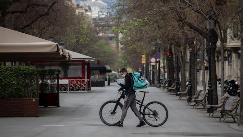 Un trabajador de Deliveroo en bicicleta por una calle de Barcelona, vacía durante el primer día laborable de la segunda semana desde que se decretó el estado de alarma en el país a consecuencia del coronavirus, en Barcelona. | David Zorrakino - Europa Press ep un trabajador de deliveroo en bicicleta por una calle de barcelona vacia durante el primer dia