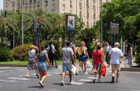 ep un termometro marca 45 grados a las 1400 de la tarde junto a unos turistas paseando en sevilla