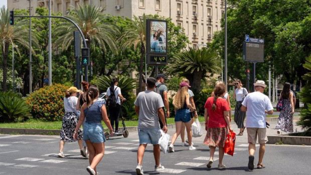 ep un termometro marca 45 grados a las 1400 de la tarde junto a unos turistas paseando en sevilla