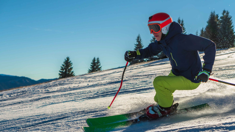 view male wearing green pants bright orange helmet while skiing sunny day 1 