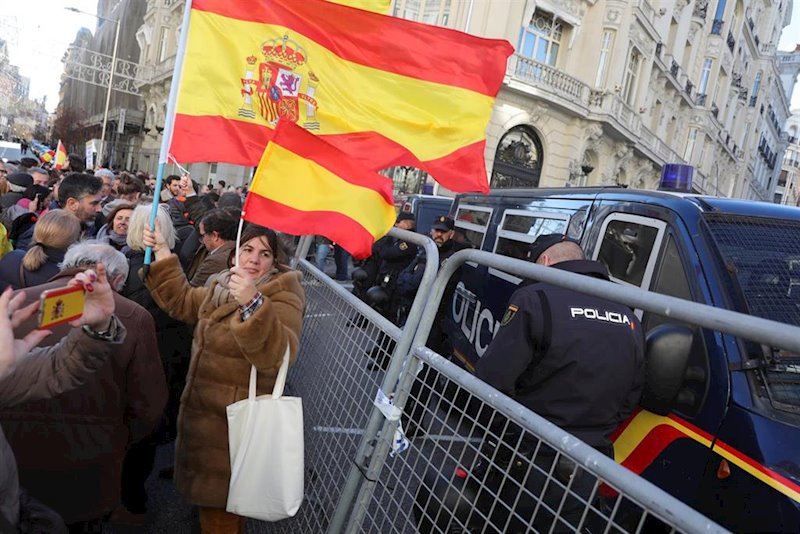 ep una mujer porta dos banderas de espana cerca de un furgon de policia en la calle genova