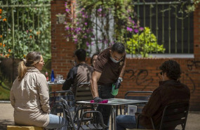 ep el propietario del bar arte y sabor desinfecta la mesa de un velador a la llegada de unos