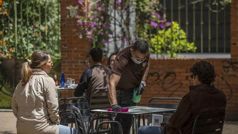 ep el propietario del bar arte y sabor desinfecta la mesa de un velador a la llegada de unos