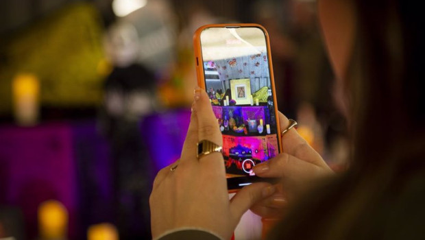 ep una persona graba con un movil un altar en la presentacion de la ofrenda del dia de los muertos