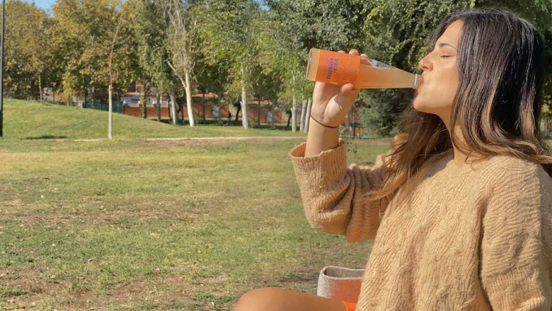 una chica bebiendo vver kombucha sabor naranjacanela