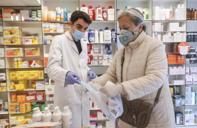 ep un farmaceutico da una mascarilla a una mujer durante el reparto de mascarillas gratuitas contra