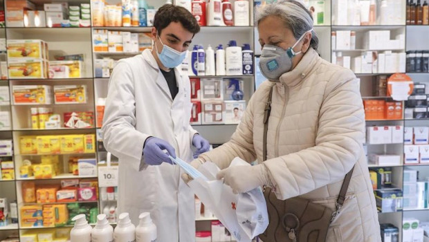 ep un farmaceutico da una mascarilla a una mujer durante el reparto de mascarillas gratuitas contra