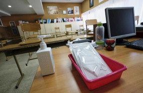 ep mascarillas y gel desinfectante en la mesa del profesor de un aula