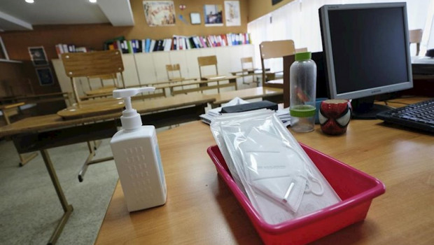 ep mascarillas y gel desinfectante en la mesa del profesor de un aula