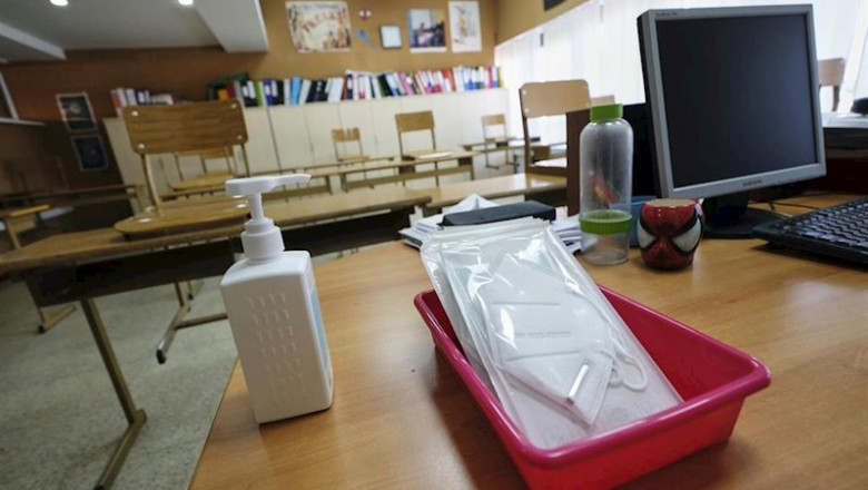 ep mascarillas y gel desinfectante en la mesa del profesor de un aula
