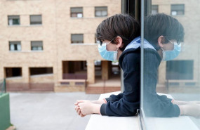 ep un nino con una mascarilla se asoma a la ventana de su casa durante el confinamiento