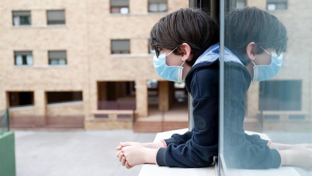 ep un nino con una mascarilla se asoma a la ventana de su casa durante el confinamiento