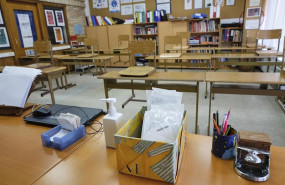 ep mascarillas y gel desinfectante en la mesa del profesor de un aula de un colegio