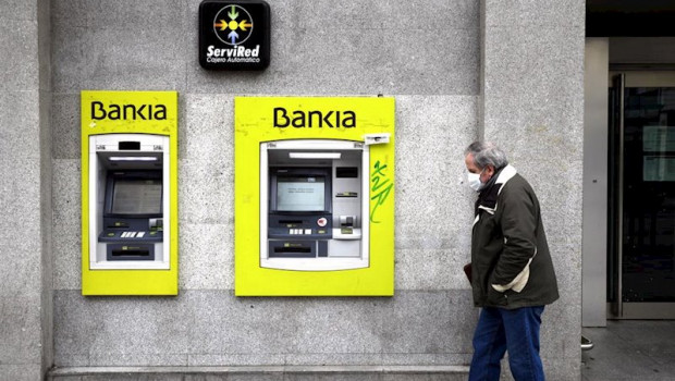 ep un hombre con mascarilla pasa por delante de un cajero de bankia
