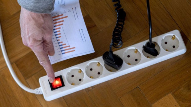 ep un hombre enciende una largadera con varios enchufes con una factura de luz en la mano