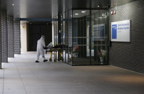 ep un sanitario protegido con un traje guantes y mascarilla sale con una camilla