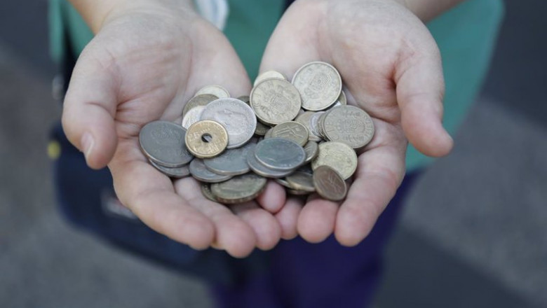 Una persona muestra un puñado de monedas de las antiguas pesetas mientras hace cola para entrar en el Banco de España. | Cézaro De Luca - Europa Press ep una persona muestra un punado de monedas de las antiguas pesetas mientras hace cola para entrar