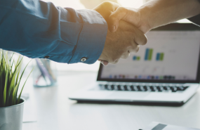 dos manos apretndose y un ordenador al fondo dos manos apretndose y un ordenador al fondo