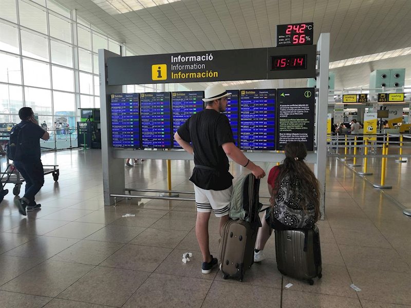 ep pasajeros en el aeropuerto de barcelona ante un panel de informacion