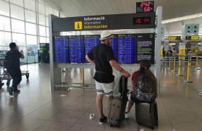 ep pasajeros en el aeropuerto de barcelona ante un panel de informacion