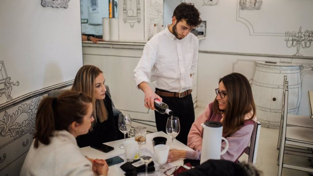 ep un camarero sirve una copa de vino a varias mujeres en una foto de archivo