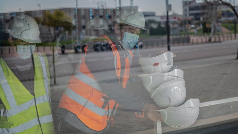 ep dos trabajadores asiaticos colocan cascos blancos de obra en el pabellon del mobile world ep dos trabajadores asiaticos colocan cascos blancos de obra en el pabellon del mobile world