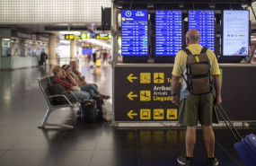 ep archivo   un hombre mira un panel de llegadas y salidas en el aeropuerto josep tarradellas